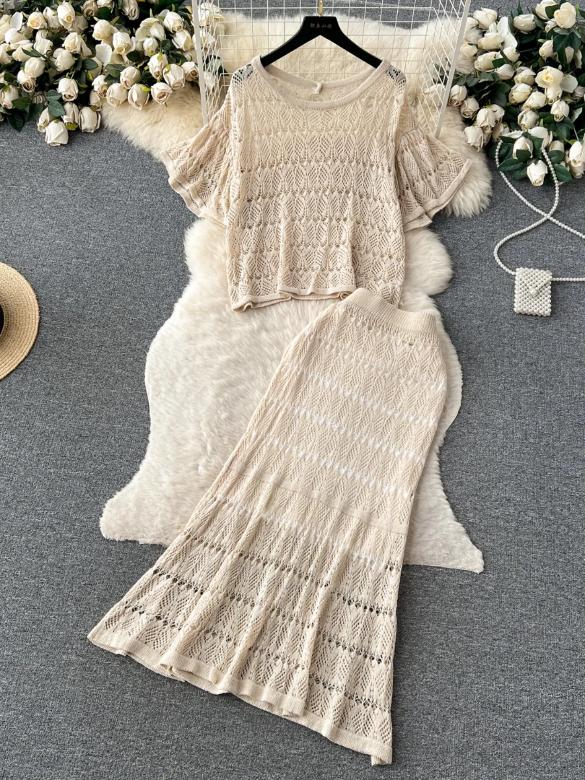 A niche vacation style hollowed out knit set for women with French round neck casual loose top+high waisted slimming wrap skirt